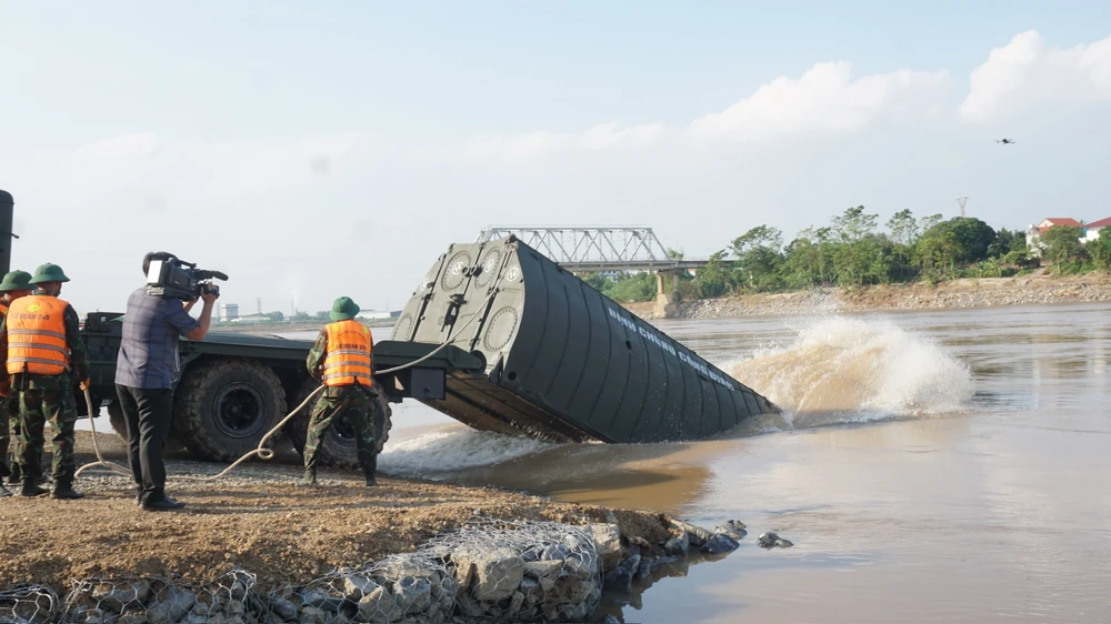 Sau khi xuống sông, các đốt phao với dây buộc sẵn được kéo vào sát bờ và neo lại, chờ tiến hành kết nối theo kỹ thuật của cầu phao dã chiến. Ảnh: XUÂN NGUYỄN