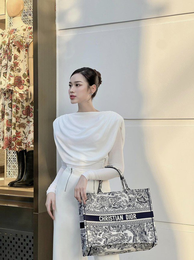 Mẫu túi Dior Tote Bag có phom dáng vuông vức, cứng cáp và kích thước lớn nên người dùng có thể đựng được rất nhiều đồ bên trong. Thiết kế này cũng có nhiều mẫu hoa văn khác nhau nhưng luôn có tên nhà mốt nổi bật chạy ngang thân túi. Hoa hậu Đỗ Thị Hà thường dùng mẫu túi này cho những chuyến du lịch, còn treo thêm một bé Labubu đáng yêu.