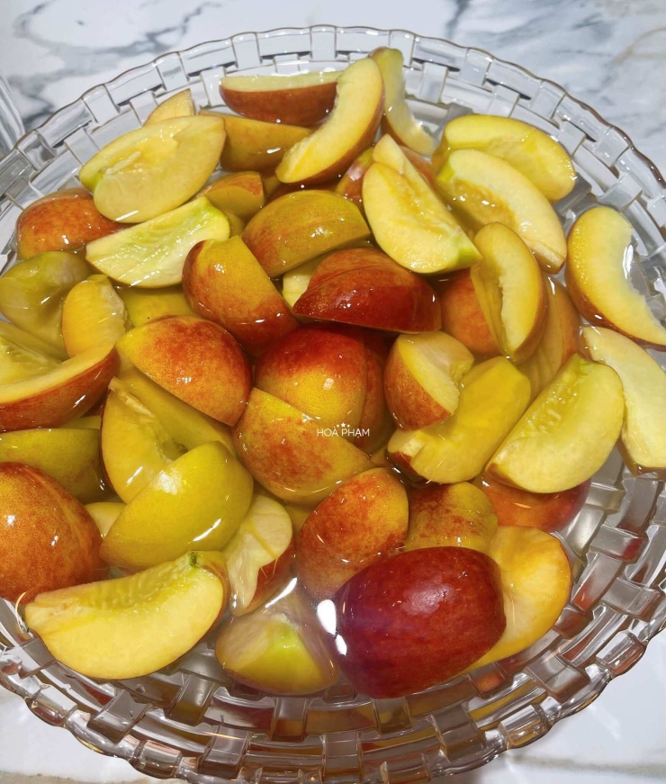 Đào bổ múi cau và ngâm vào bát nước nước loãng có vắt thêm nửa quả chanh.