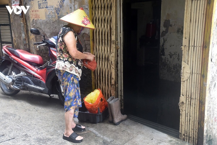 Bà Cù Thị Bắc chuẩn bị xỏ đôi ủng cao su để lội vào căn nhà nơi đang sinh sống tại số nhà 14, ngõ 42 Giang Văn Minh. Dù nước ngoài ngõ đã rút, tầng một ngôi nhà của bà vẫn còn ngập, buộc gia đình phải sinh hoạt tạm trên tầng hai.