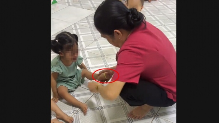 Cảnh bảo mẫu đeo dây thun vào chân bé và bắn (ảnh cắt từ video chia sẻ MXH)
