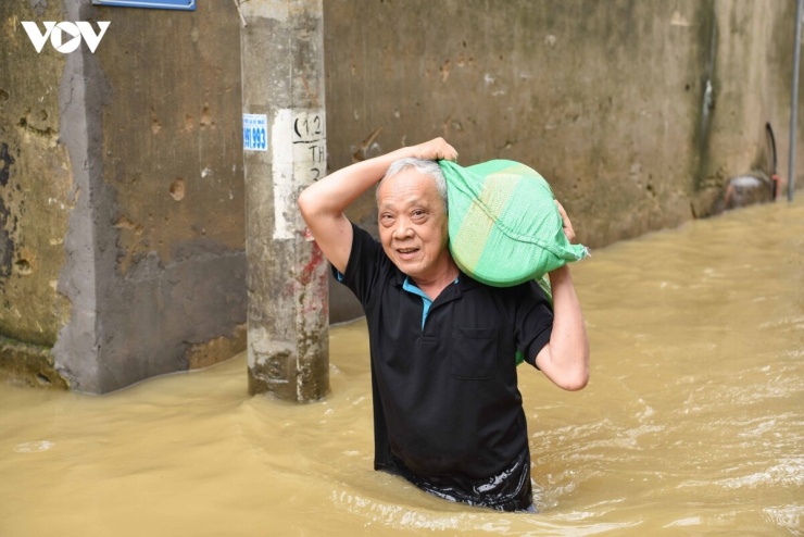 Mực nước sông Cầu dâng cao khiến nhiều khu vực tại tổ dân phố Thổ Hà, phường Vân Hà, tỉnh Bắc Ninh muốn di chuyển người dân chỉ còn cách khuân, vác đồ lên người để tránh bị ướt.