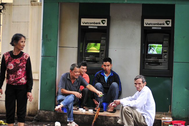 Những người dân lao động ngồi trong một cây ATM trên đường Chu Văn An &#40;Ba Đình&#41;, uống trà nóng và hút thuốc lào để tránh rét.