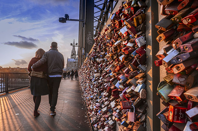 Một cặp tình nhân dìu nhau đi dạo trên cây cầu tình yêu Hohenzollern, thành phố Koln