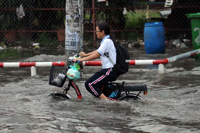 Học sinh trở về nhà trên con đường ngập nước Phan Anh. “Đường này ngập suốt mà. Mưa là ngập. Chỉ tội mấy phụ nữ mang bầu và các em học sinh phải bì bõm kiểu lội nước”, anh Lê Tứ ngụ quận Bình Tân chia sẻ.