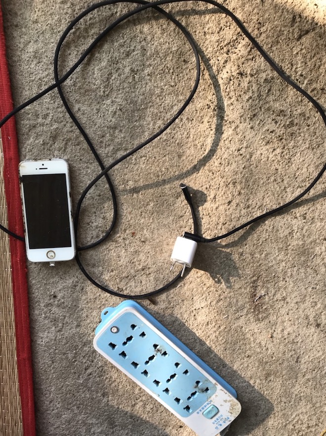 T. kéo một ổ điện từ trong nhà ra ngoài võng để cắm “củ sạc” iPhone và vừa sạc vừa sử dụng điện thoại.