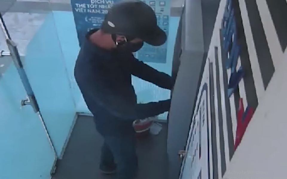 Một nghi phạm đang thực hiện hành vi lắp đặt thiết bị tại cây ATM.