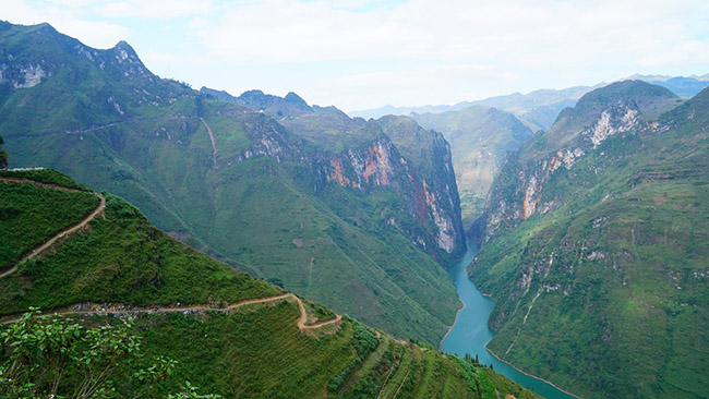 Khi đến Mã Pì Lèng sẽ thấy con sông Nho Quế. Con sông khắc tên mình lên 46km trên dải đất Việt Nam, và chảy qua lớp đá tai mèo lởm chởm của hệ thống công viên địa chất toàn cầu cao nguyên đá Đồng Văn, nhờ đó tạo nên dòng chảy mạnh với vô số thác ghềnh trắng xóa xen giữa những hẻm vực, thung lũng ẩn hiện giữa non cao núi bạc, mây trời Hà Giang tạo nên cảnh sắc thiên nhiên hùng vĩ. (Ảnh: Triệu Quang)