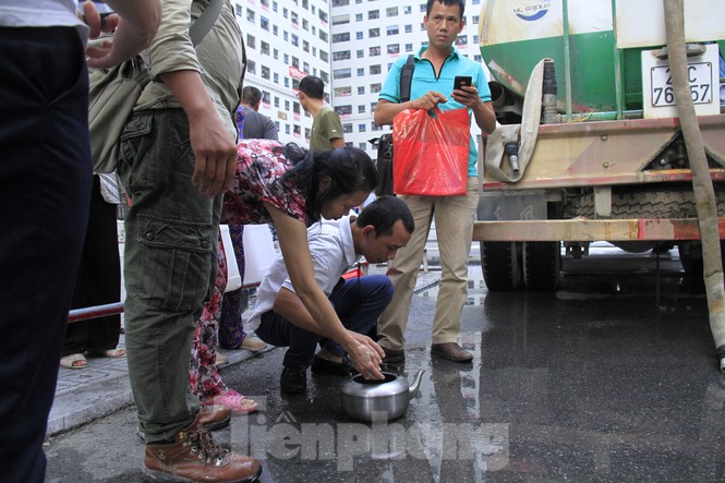 Sau khi xe nước thứ hai đến, nhiều người vẫn tiếp tục không lấy nước vì phát hiện có mùi tanh. Ảnh: Trường Phong