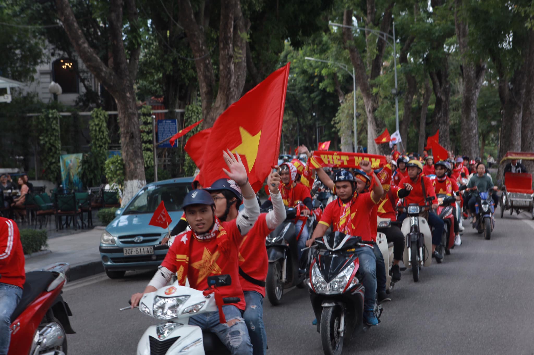 Đoàn diễu hành nhuộm đỏ phố phường, vẫy tay chào người đi đường.