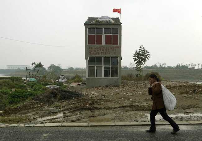 Một người phụ nữ đi ngang qua một "ngôi nhà đinh" ở ngoại ô Nam Kinh, nơi đất sẽ được sử dụng cho một dự án đất ngập nước, theo truyền thông địa phương.
