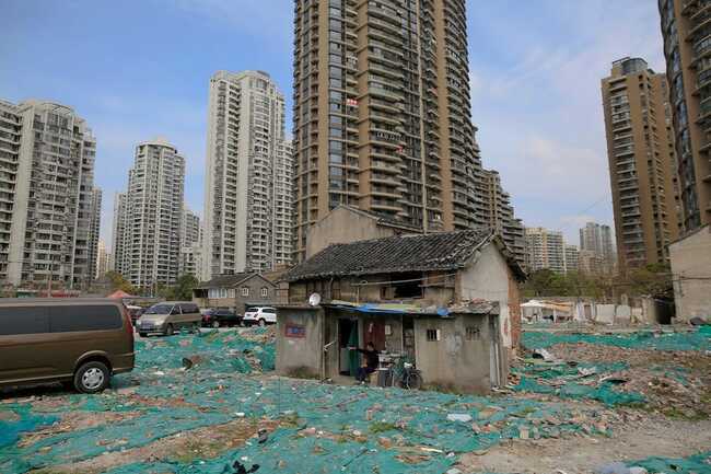 Cư dân của khu vực Guangfuli của Thượng Hải đã quyết định không rời khỏi nhà của họ, tạo ra cả một "khu phố đinh". Tao Weiren ngồi trước ngôi nhà hai tầng của mình ở đó, hiện được bao quanh bởi các tòa nhà chung cư cao cấp.