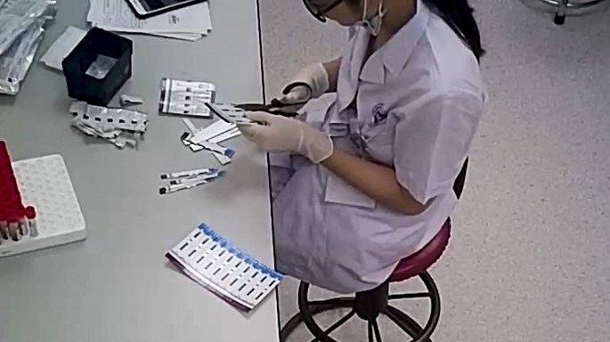 Kỹ thuật viên cắt đôi que thử xét nghiệm HIV và viêm gan B.