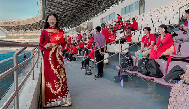 Milan Phạm sang Philippines cổ vũ cho đội tuyển bóng đá nam. Cô diện trang phục áo dài có thêu họa tiết, trên nền đỏ được coi là sự may mắn.
