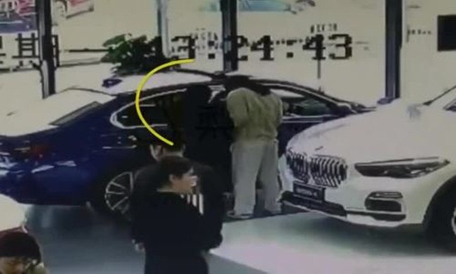 Hình ảnh từ camera cho thấy nam thanh niên đứng gần xe BMW màu xanh sau đó có hành động lén lút rồi rời đi.