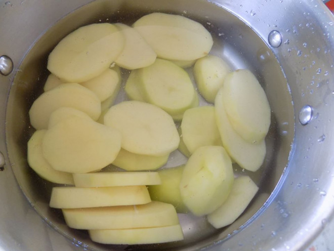 Khoai tây đã gọt vỏ, cắt lát cho hết vào nồi, đổ nước ngập khoai , bắc lên bếp luộc . Khi khoai chín, đổ khoai ra rổ để ráo nước.