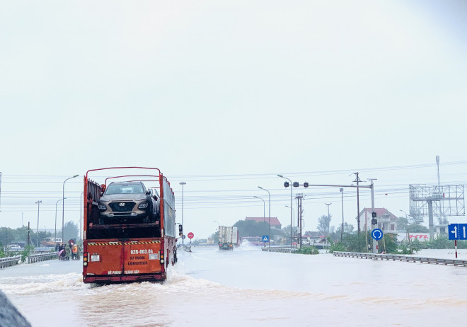 Những chiếc xe tải di chuyển chậm qua tuyến đường tránh ngập lụt nặng.