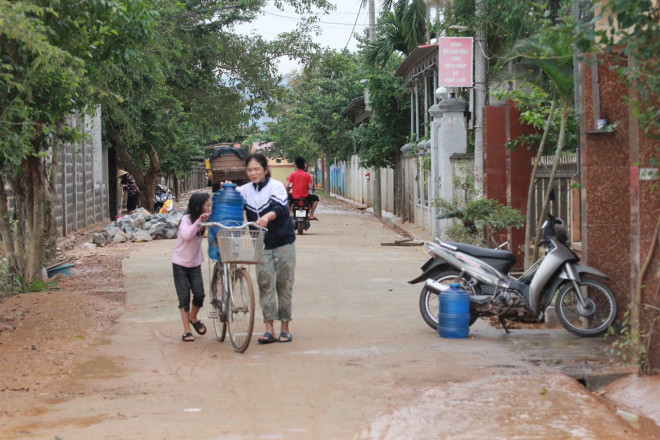 Em bé cùng mẹ nhận hỗ trợ nước sạch.