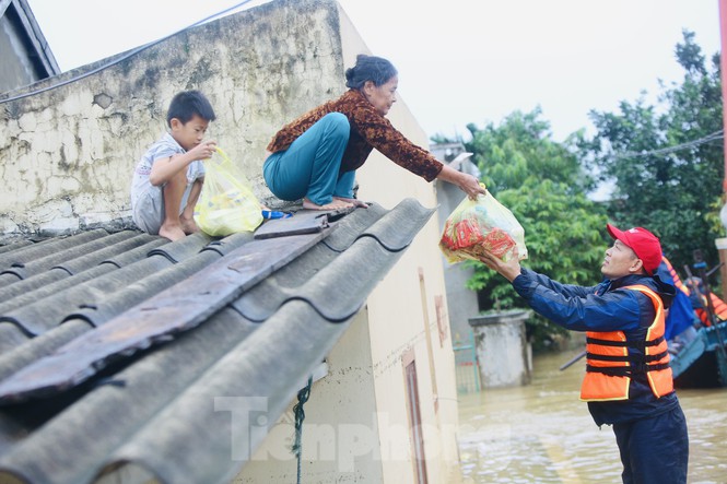 &nbsp; Cháu bé cùng bà đứng trên mái nhà nhận những gói mì tôm cứu trợ từ hội từ thiện.