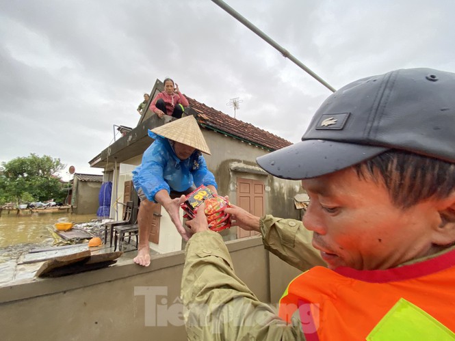 &nbsp;Người đàn ông nhận hàng cứu trợ và chuyển sang cho vợ rồi mới trèo tường lên mái ngói vào nhà.