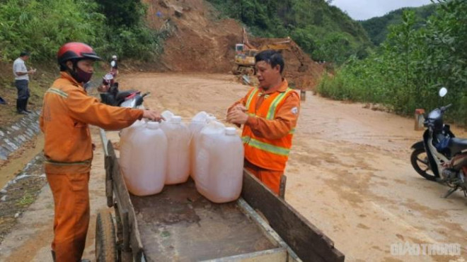 Anh Nguyễn Văn Thìn (bên phải 45 tuổi, thị trấn Prao, Đông Giang, Quảng Nam), công nhân Công ty CP Quản lý và xây dựng đường bộ Quảng Nam - Đà Nẵng chuẩn bị xăng dầu cho tổ máy hót dọn "núi đất đá" sạt lở taluy dương tại Km449+100 đường HCM nhánh Tây, tỉnh Quảng Nam