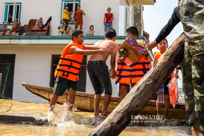 Những đứa trẻ mang áo phao thi nhau bơi ra ngoài nhận đồ tiếp tế từ đoàn từ thiện.