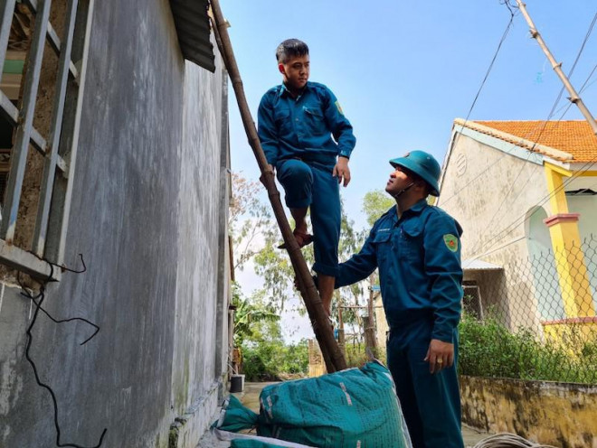 Lực lượng bộ đội, dân quân hỗ trợ người dân chằng chống nhà cửa. Ảnh: TN