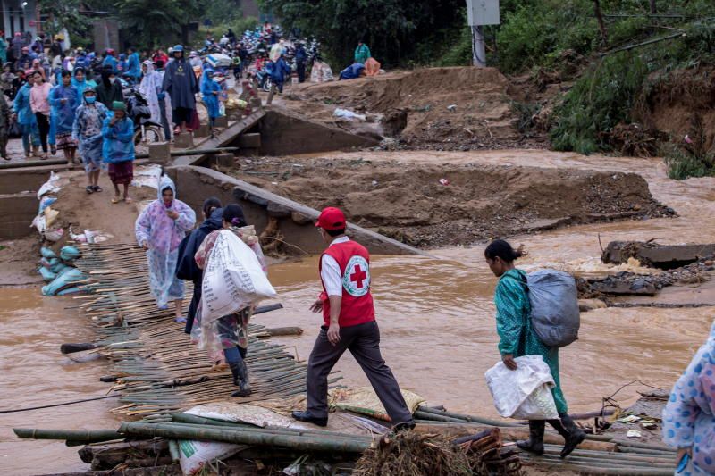 Hãng Reuters đăng tải bức ảnh&nbsp;người dân mang theo hàng cứu trợ đi qua một cây cầu bị sập sau vụ sạt lở đất ở tỉnh Quảng Trị, Việt Nam. Ảnh: Reuters&nbsp;