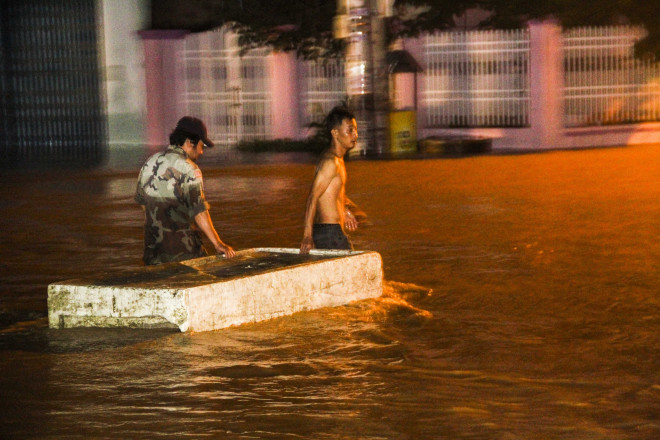 Người dân sử dụng các bè bằng xốp để đưa phương tiện qua bên kia đường. Ảnh: Trương Định