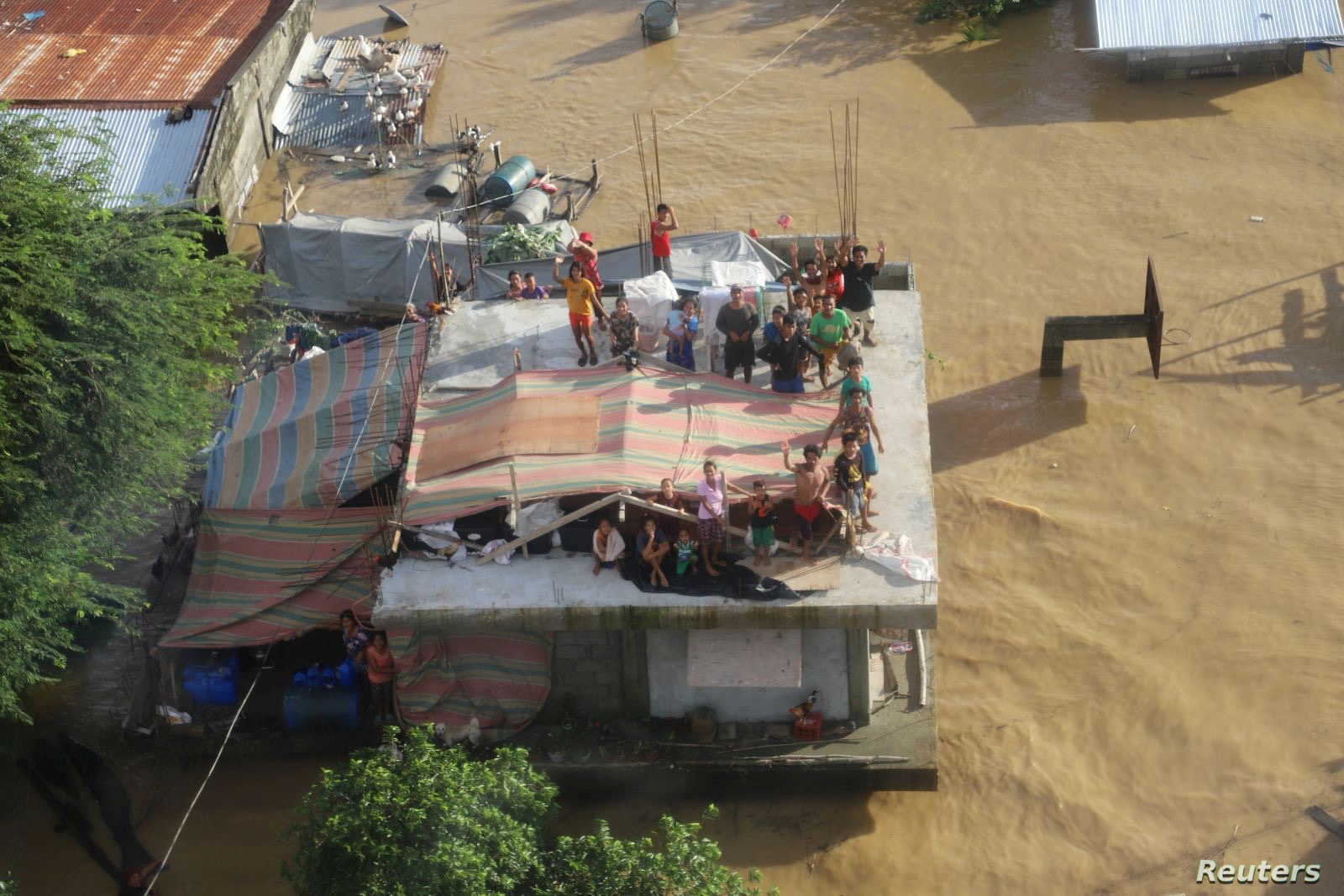 Một gia đình Philippines bị mắc kẹt trên mái nhà do lũ lụt sau bão Vamco (ảnh: SCMP)