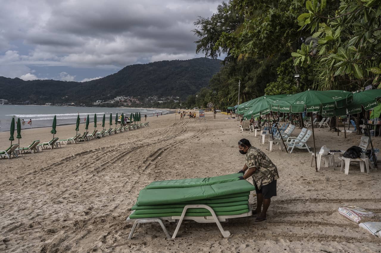 Một người dân thu dọn ghế tắm nắng trên bãi biển ở thị trấn Patong, đảo Phuket, Thái Lan, hôm 1/10. Ảnh: NYT