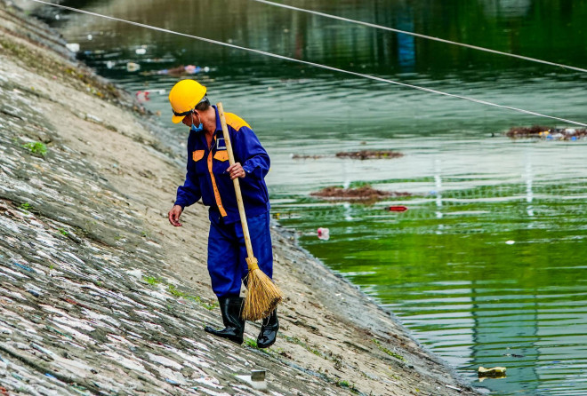 Bên cạnh đó, công nhân môi trường đang dọn vệ sinh khu vực bên bờ sông Tô Lịch