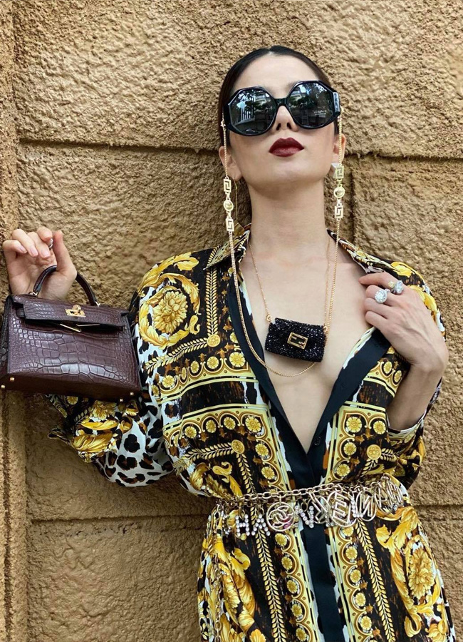 Cô phối váy sơ mi Versace khoét cổ sâu hun hút với túi Hermès và phụ kiện đến từ thương hiệu Chanel.
