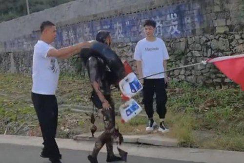 Chú rể bị tạt sơn đen kín người, đeo lốp xe và những hộp sơn được nối bằng dây trên cổ.