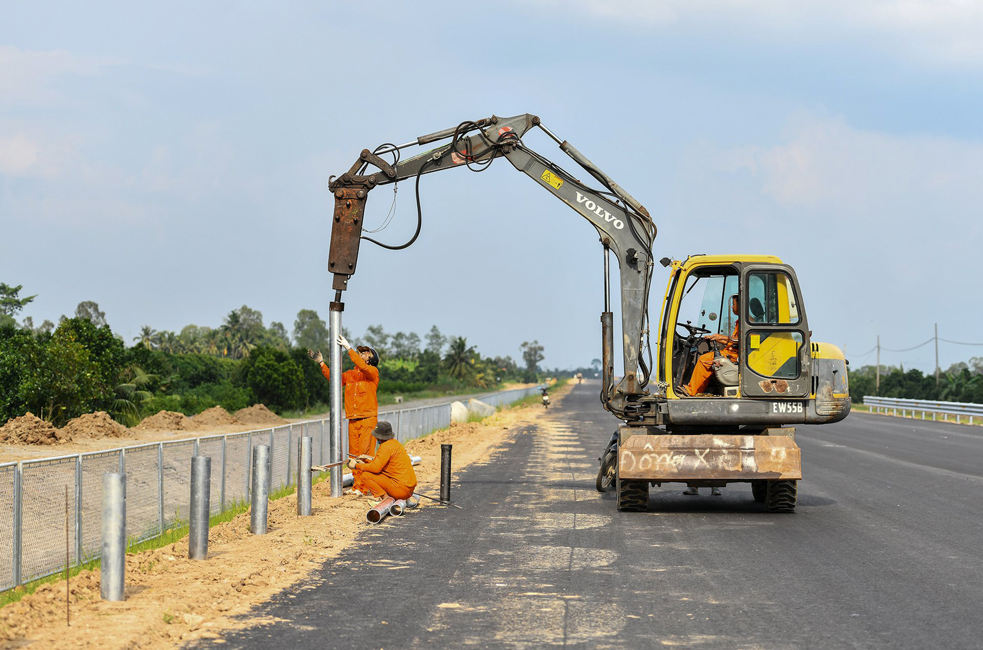 Nhóm công nhân thi công song song lắp đặt hệ thống rào chắn, lan can, biển báo… hai bên cao tốc.