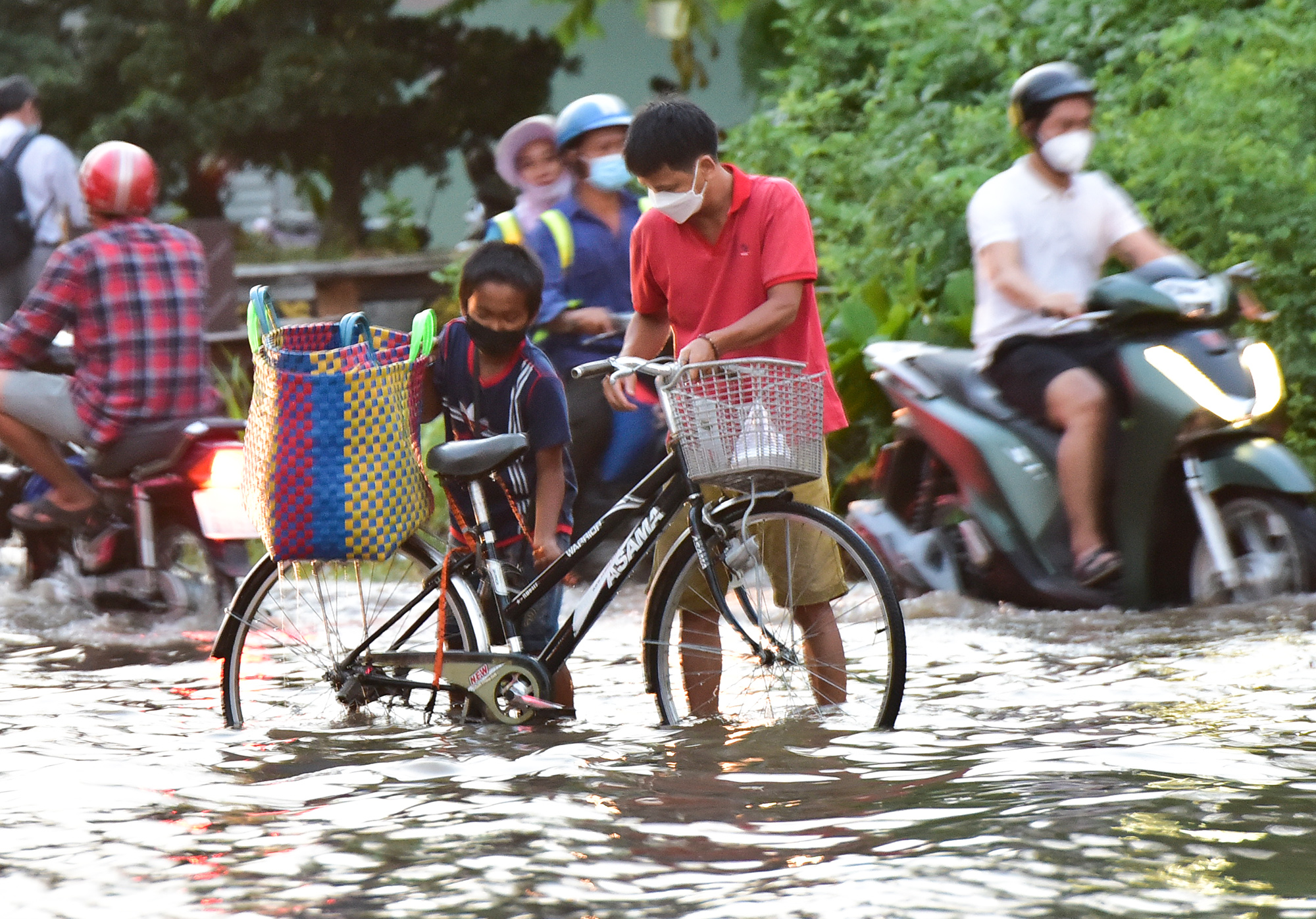 Đây là đoạn đường bị trũng thấp do dừng thi công nhiều năm qua, mặt đường nhiều ổ trâu, ổ voi, gạch đá lởm chởm khiến nhiều người né phần ngập di chuyển khó khăn. Trong ảnh, một cậu bé chạy đạp được người dân giúp đỡ sau khi bị té do vấp phải ổ trâu chìm dưới mặt nước.