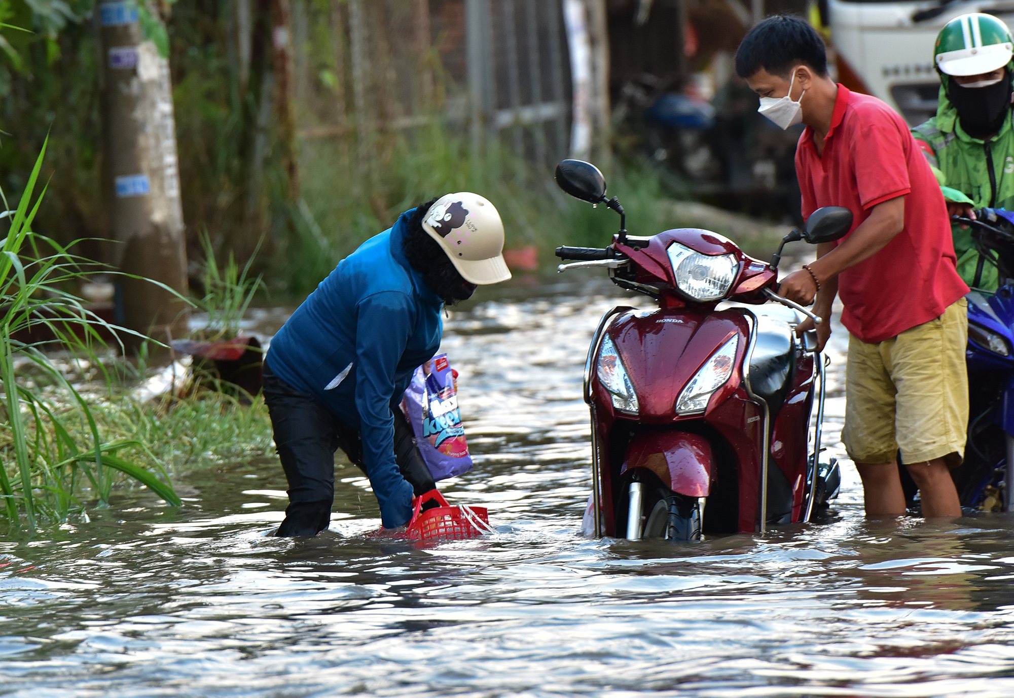 Người phụ nữ này được người dân bên đường giúp đỡ dựng xe, đồ đạc gồm gạo, đồ ăn bị rơi chìm trong nước phải mò tìm, xe ngâm nước bị chết máy.