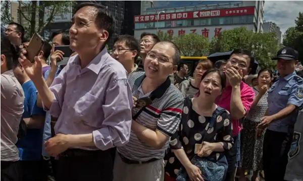 Các bậc phụ huynh đứng chờ bên ngoài một trường trung học trong khi con đang thi gaokao. Ảnh: Kevin Frayer/ Getty Images.