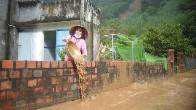 Người dân dọn dẹp bùn đất ngổn ngang sau khi đất đá sạt lở trên núi Cấm đổ về