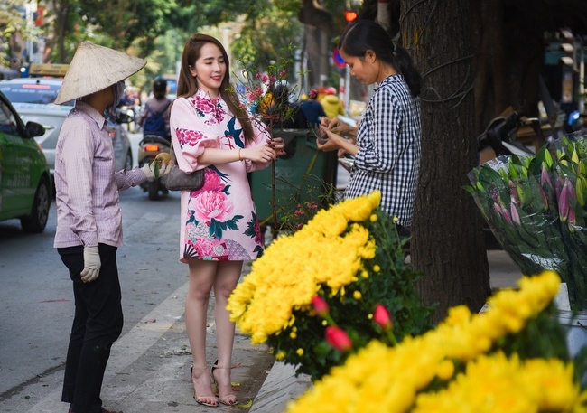 Quỳnh Nga thu hút ánh nhìn với áo dài kiêu sa khi ra chợ mua hoa và trái cây.
