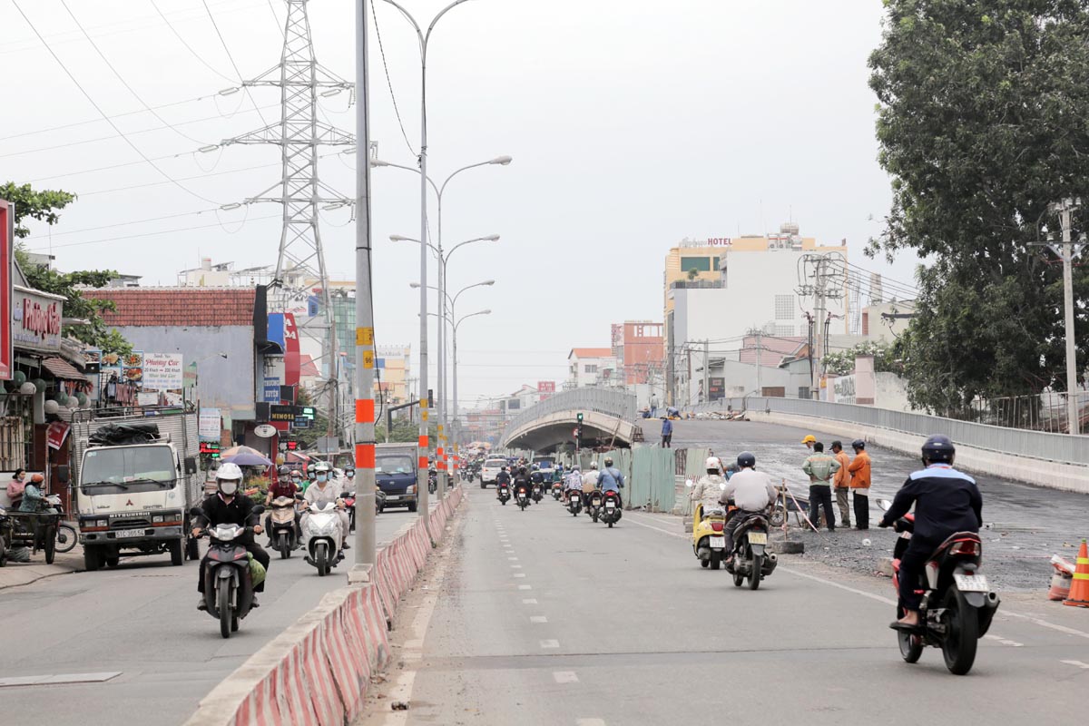 Công nhân đang thi công trải nhựa, hệ thống lưới điện, lan can của nhánh 1 của cầu.