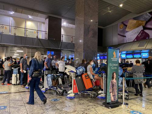 Hành khách xếp hàng chờ làm thủ tục khởi hành tại sân bay quốc tế ở TP Johannesburg - Nam Phi hôm 26-11 Ảnh: REUTERS