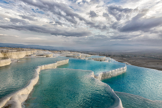 Pamukkale, Denizli, Thổ Nhĩ Kỳ: Các hồ bơi 17 tầng của Pamukkale (“lâu đài bông” trong tiếng Thổ Nhĩ Kỳ) đẹp tuyệt vời. Làn nước màu trắng sữa ấm áp phản chiếu hoàn hảo bầu trời trong xanh của nơi này.&nbsp;
