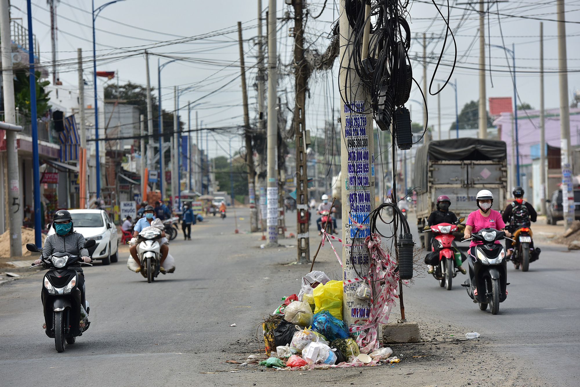 Đủ các loại trụ điện chiếm hết không gian mặt đường mới, người tham gia giao thông phải luồn lách để di chuyển, nhiều trụ trở thành nơi tập kết rác.