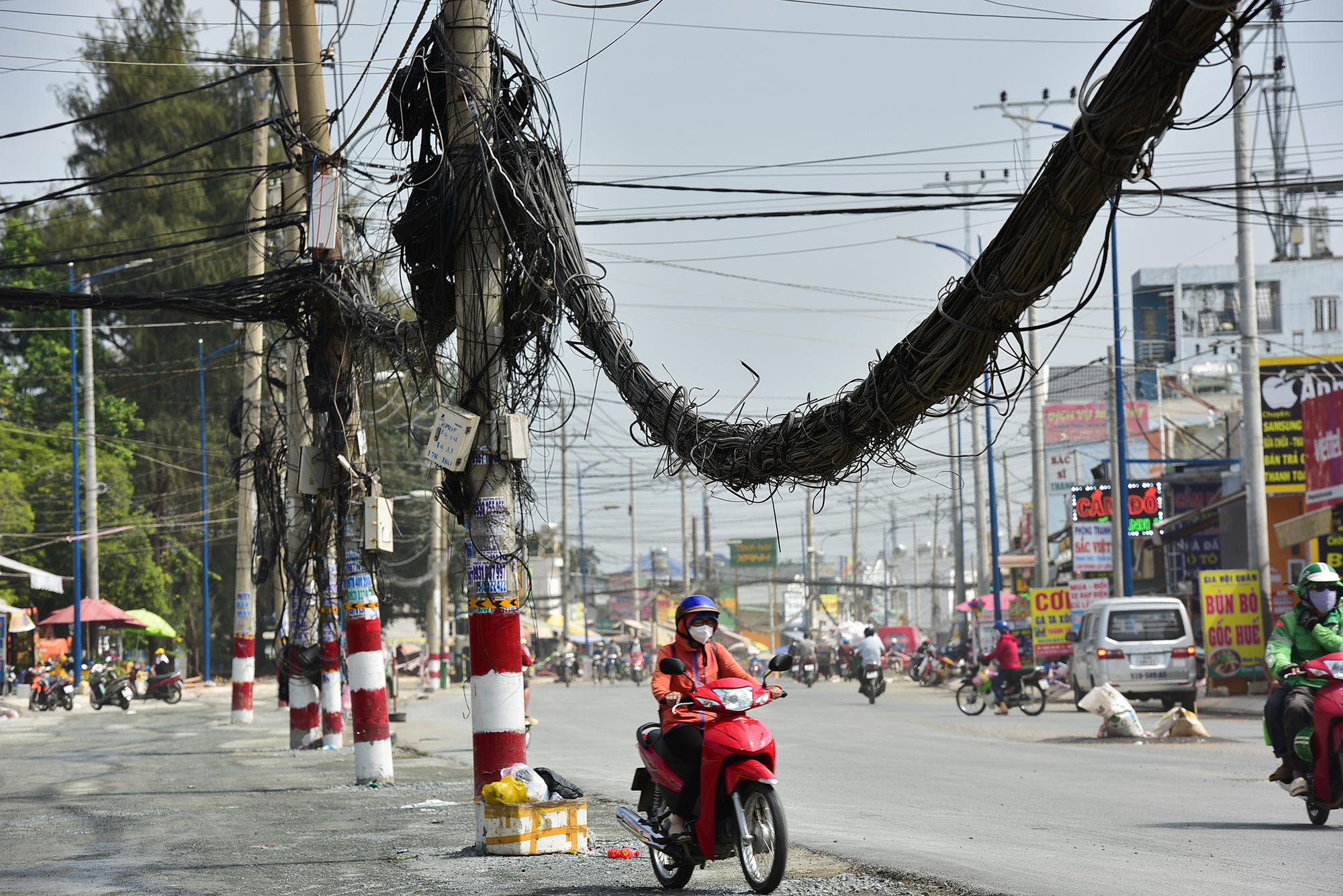 Những bó dây cáp lòng thòng giữa các trụ điện, nhiều chỗ võng xuống sát đầu người đi đường.