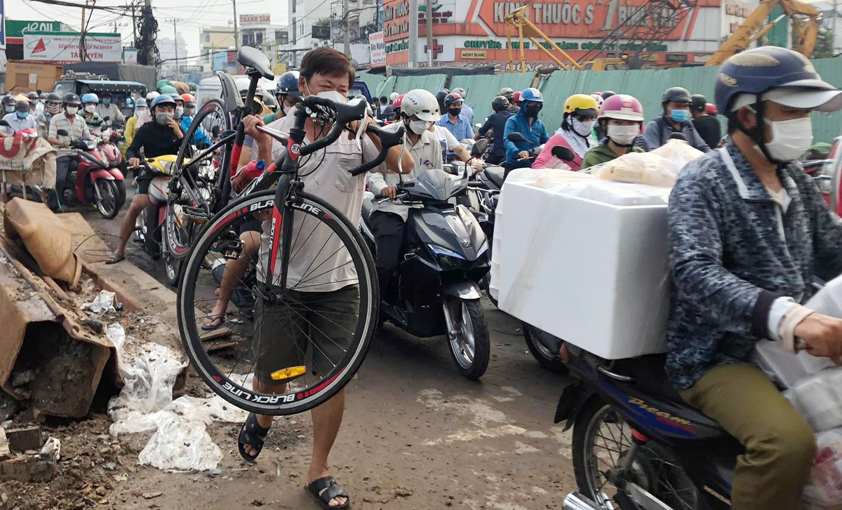 Người đi xe đạp phải khiêng xe để vượt qua đoạn ùn tắc giao thông. Đến gần trưa cùng ngày, tình hình giao thông qua khu vực vẫn còn ùn ứ.