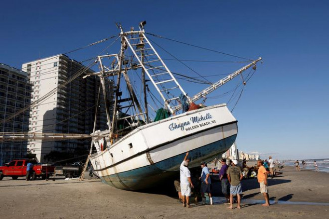 Ngư dân đang tìm cách đưa một chiếc thuyền câu tôm lớn trở lại mặt nước sau khi bị bão Ian cuốn vào bờ biển ở Myrtle Beach, South Carolina - Mỹ hôm 1-10. Ảnh: REUTERS