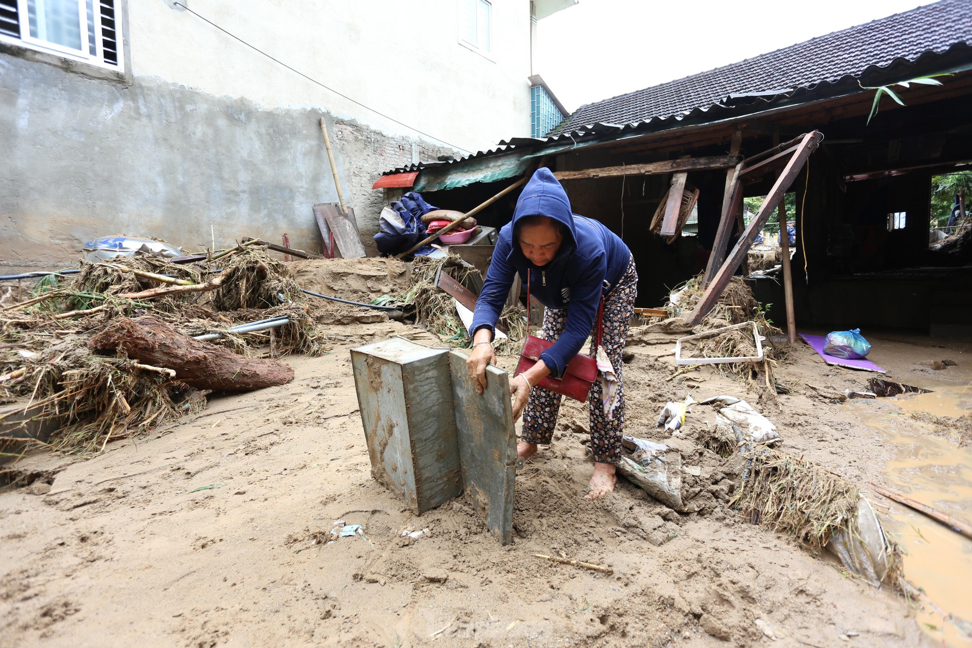 Bà Vang Thị Bình (65 tuổi, khối 1, thị trấn Mường Xén) nhặt nhạnh những gì còn sót lại sau lũ. "Mất hết rồi, không còn gì nữa", bà nghẹn ngào.