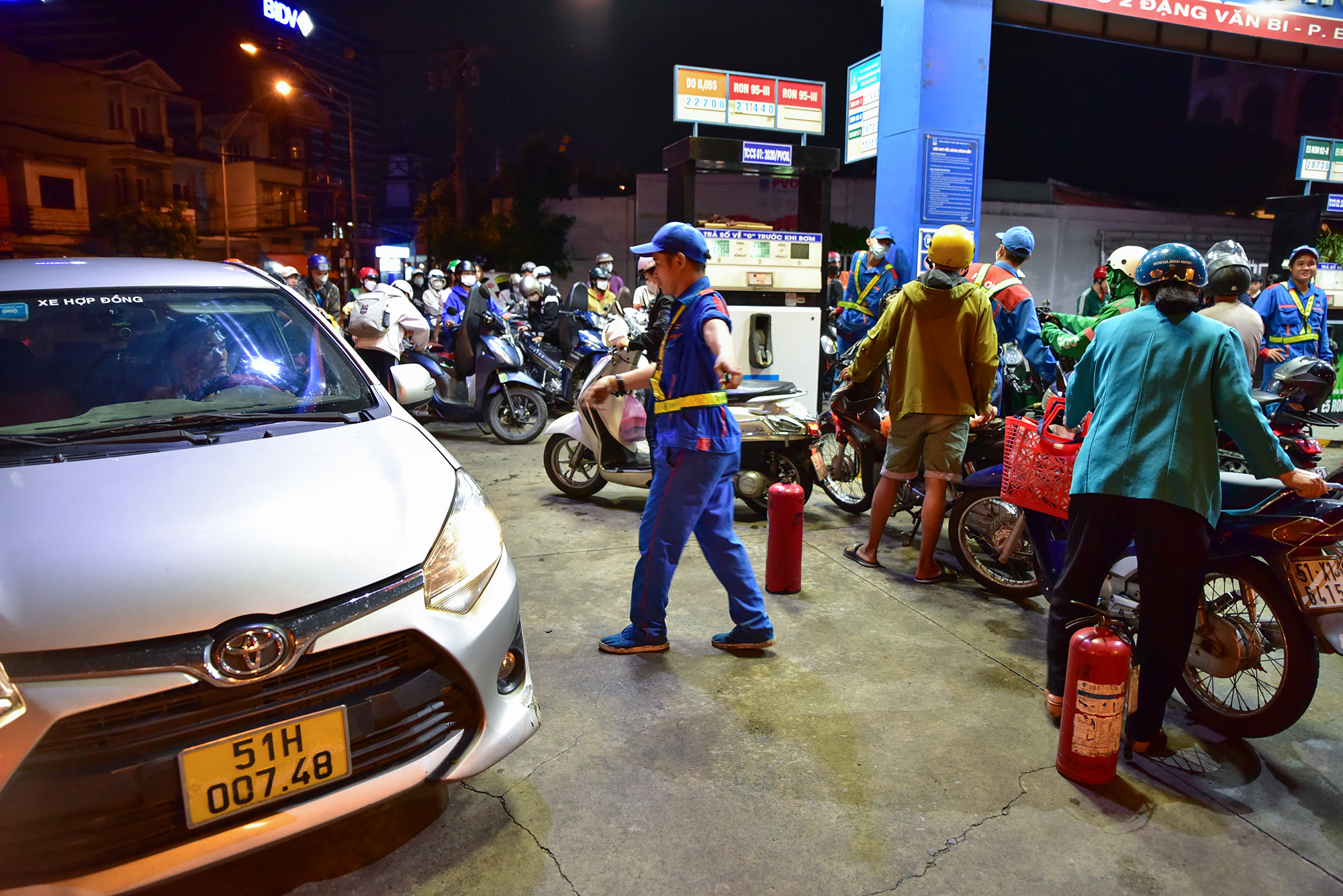 Bên ngoài, hàng chục người đứng, ngồi vạ vật chờ đợi bạn đồng hành vào đổ xăng. Nhân viên cây xăng liên tục phân làn, điều tiết lối ra vào để khách di chuyển được thuận lợi hơn.