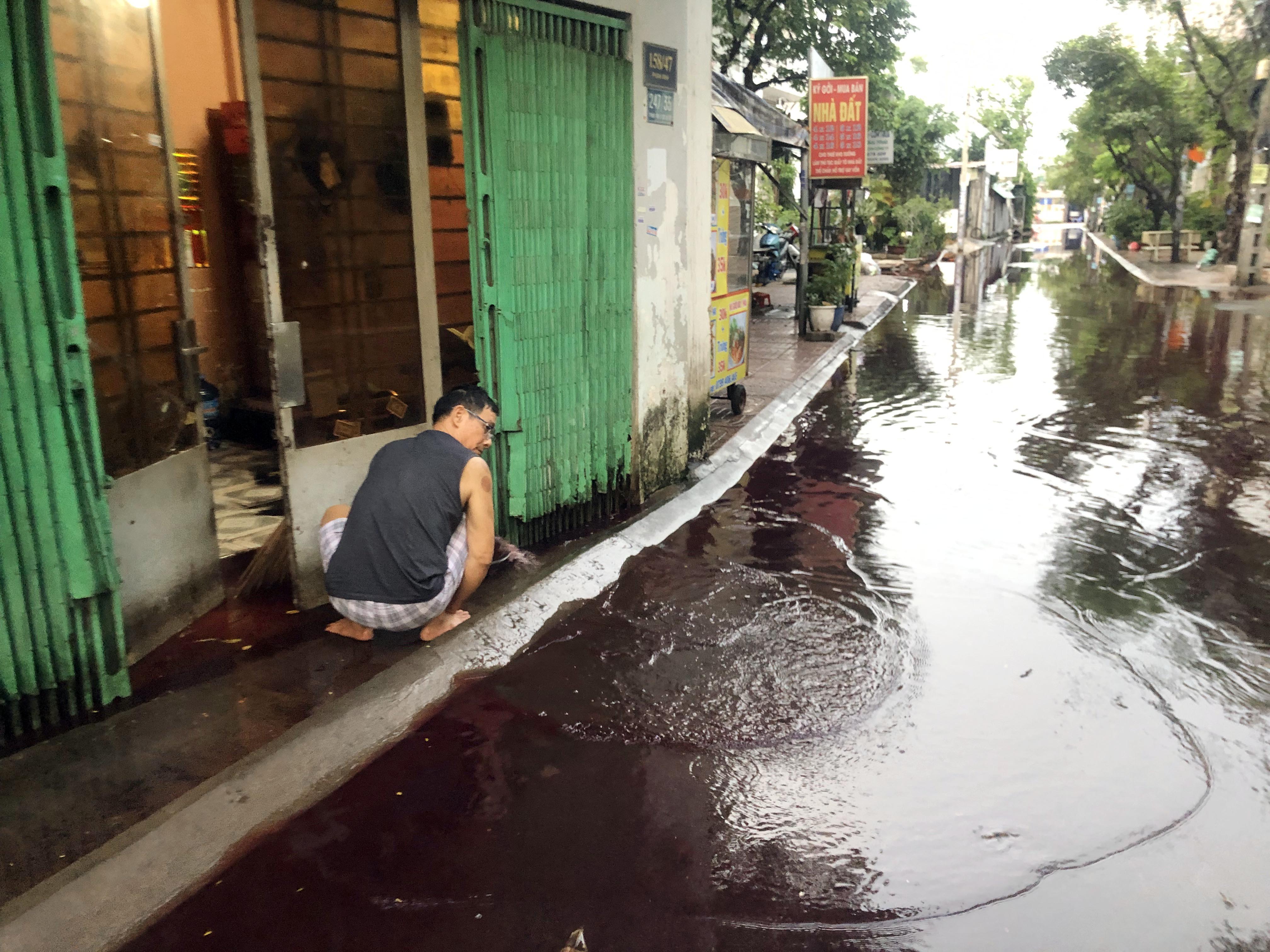 Người dân tát nước ngập trong nhà ra ngoài.